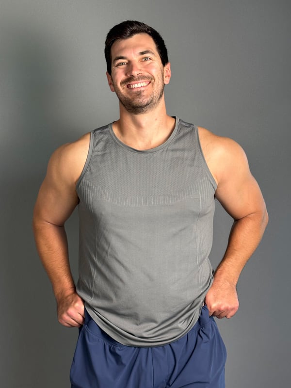 Coach is posing with a big smile wearing sleeveless gray undershirt.